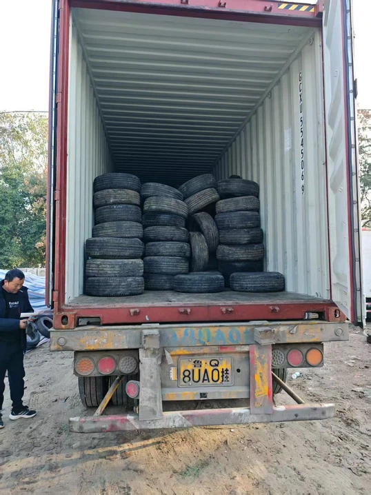 Second-hand tires stacked near shipping container for export Second-hand tires stacked near shipping container for export